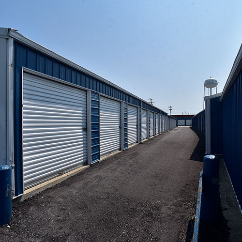 Photograph of a blue metal self storage building and paved parking lot