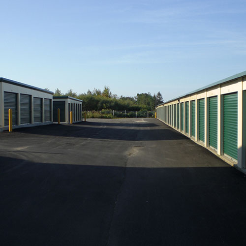 single story metal self storage buildings with metal roll-up doors and paved parking