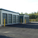 two self storage buildings green metal roll up doors and wide paved parking areas