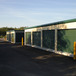 rows of green self storage unit doors with paved parking spaces between single story self storage buildings