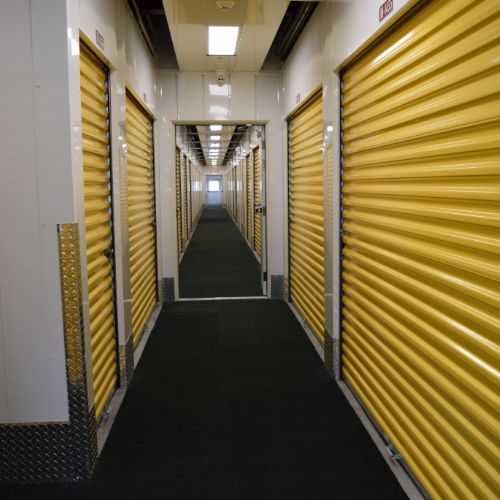 two rows of temperature controlled self storage units on either side of a brightly lit interior hallway