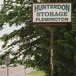 a sign that reads Hunterdon Storage Flemington with pine trees and a road in the background