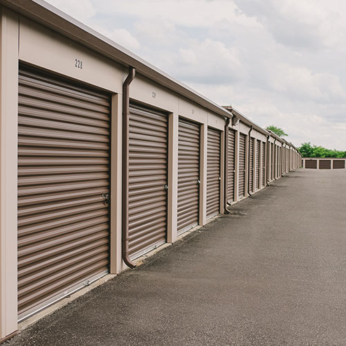 a row of brown self storage units with wide paved parking spaces in front of them