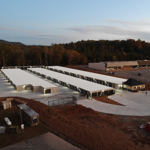 aerial photograph of a fenced-in self storage facility with three buildings taken at dusk