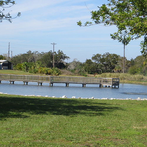 photograph of a pond with a dock that ends in a platform in the middle of the pond