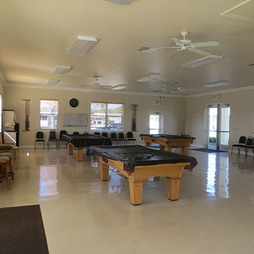  photograph of the interior of a recreation building with pool tables around the room