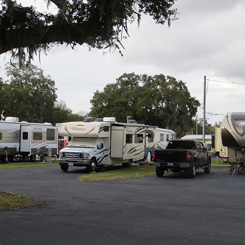 photograph of paved parking spots with recreational vehicles parked and hooked up to utilities